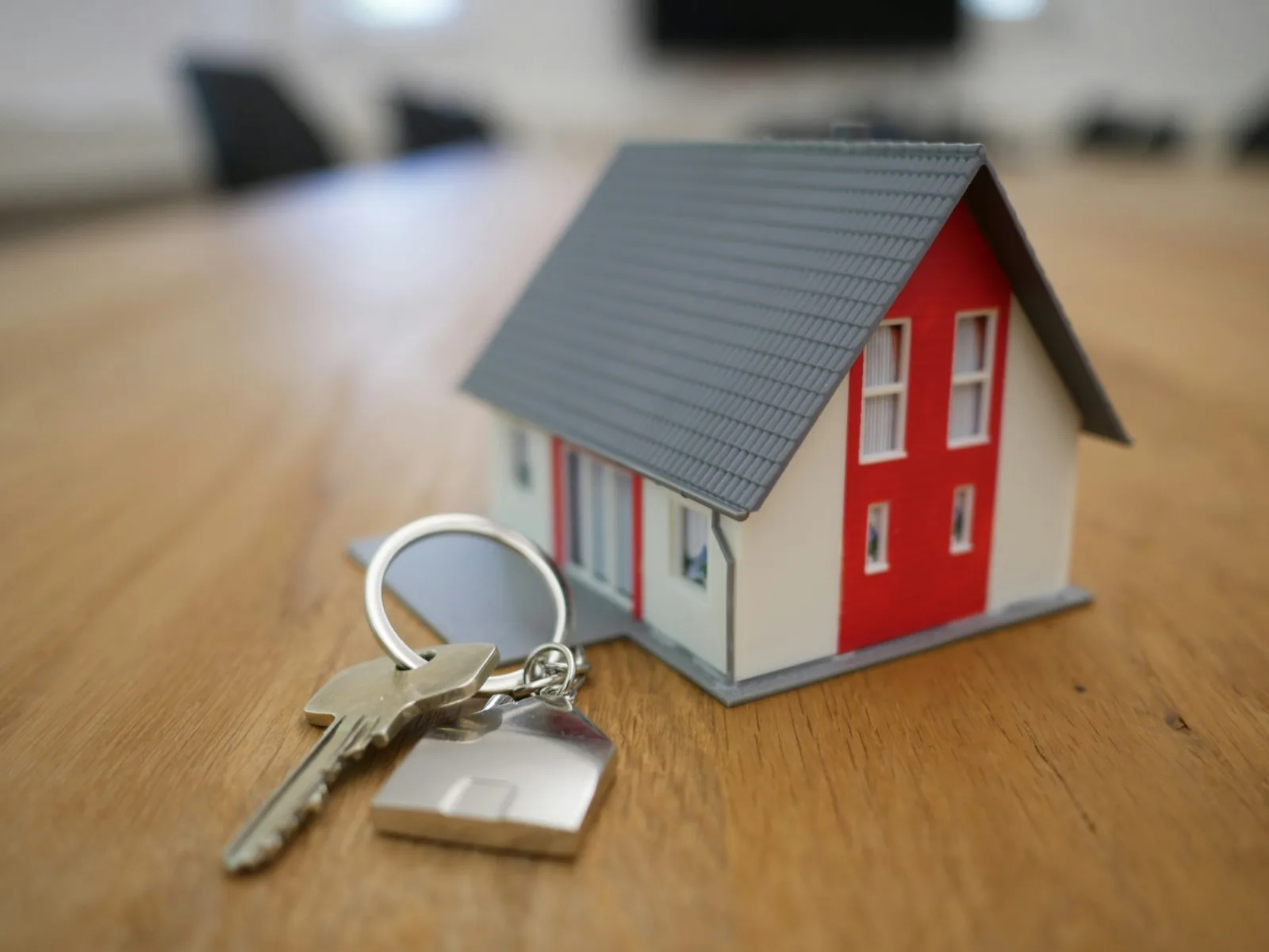 A house key and model house on a wooden table, representing a property sale