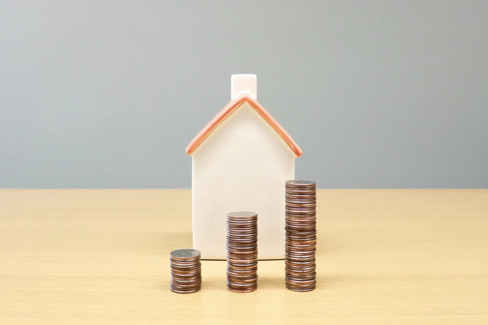 A model house beside rising stacks of coins, representing growing property value